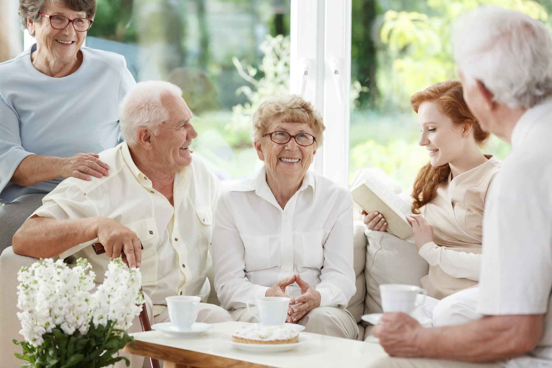 Residents and a caregiver sharing tea and conversation at ADL Assisted Living